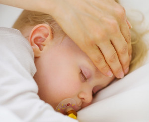 Adult hand checking the fever of a child with his hand